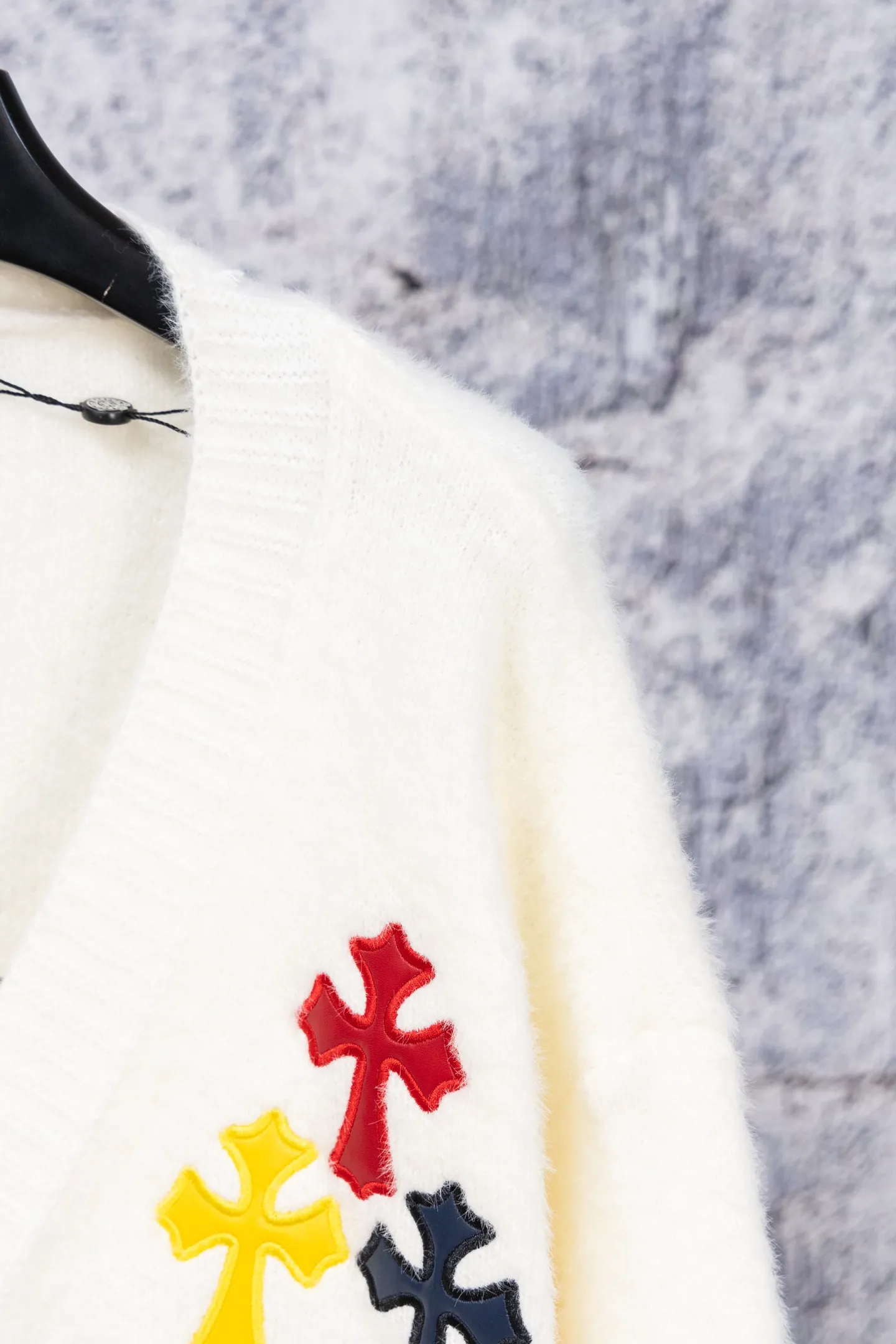 P300 Chrome Hearts CH Chrome Hearts 2026 new cross loose knitted V-neck cardigan Fabric: Made of plush textured knitted material, soft to the touch and with a lazy atmosphere; Decoration: Red, yellow, and black cross ornaments on the chest, paired with brand logo patches, which are iconic elements of street fashion brands (such as Chrome Hearts style), enhancing visual recognition; Version: Loose version + single-row metal button design, combining casual feeling and practicality. 2. Style and Adaptation Style: It combines dark street style and gentle knitted texture, which belongs to the tone of "sweet and cool mix"; Scenario: Can be worn with a T-shirt/suspender to create a daily street look, or can be layered with a shirt for light casual wear. Color: Black White Size: M L XL